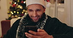 Christmas, happy man and relax with phone for shopping, social media or funny meme in home. Person, mobile and smile in lounge for season message, charity donation or planning holiday accommodation