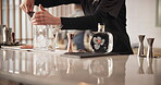 Hospitality, man and bartender with ice in glass for catering, service and mixology technique. Professional, server and hands preparing alcohol with utensil for restaurant, beverage or order at event