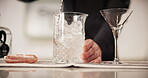 Person, service and bartender stirring ice in glass for catering, hospitality and mixology technique. Professional, server and hands preparing alcohol with utensil for restaurant, beverage and event