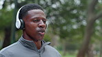 Fitness, park and black man with headphones for music, playlist and radio for workout. Sports, nature and person listening to audio for marathon training, exercise and running outdoors for health