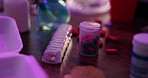 Drugs, addiction and pills on dirty table with neon lights, pharmaceutical narcotics and mess at night. Danger, mental health and prescription medicine with risk, abuse and opioid crisis in dark home