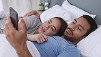 Couple in bed with smartphone for meme, social media online content or notification and laughing together cuddling or hugging in bedroom. In love man and woman on cellphone home on the weekend