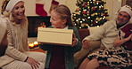 Christmas, big family and girl with gift, giving and present in home living room with sofa. Grandparents, parents and girl for party, celebration and festive holiday with santa hat on lounge couch