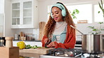 Happy girl, listening or cutting ingredients with headphones for music or cooking recipe in kitchen. Young, female person or freelancer with knife for fun meal preparation or hospitality at house