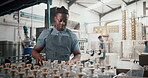 Employee, black man and packaging alcohol at distillery with gin bottles for manufacturing and production at warehouse. Male person, business and stocktaking at factory for delivery and supply chain