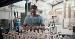 Happy, black man and packaging alcohol at distillery with gin bottles for manufacturing and production at warehouse. Male person, employee and stocktaking at factory for delivery and supply chain