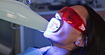 Person, teeth whitening and mouth in dentist chair with LED torch, process and cheek retractor at clinic. Woman, patient and light for change, transformation and lamp for oral wellness at hospital