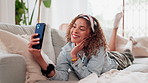 Happy girl, selfie and lying with phone on sofa for memory, picture or enjoying holiday in living room at home. Young, female person or user with smile on mobile smartphone for photography at house