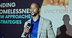Talking, serious and man with mic, seminar and speech for ending of homelessness, stage and event. Workshop, presentation and public speaking in conference, communication and black person with pitch