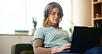 House, laptop and woman with headphones, typing and internet with connection, sound and podcast. Person, apartment and girl in lounge, computer and headset for live streaming, happiness and comfort