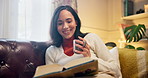 Woman, coffee and reading book to rest in home, literature and fiction novel with matcha for laugh. Female person, drinking tea and rest with funny story in living room, hot espresso and page humor