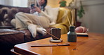 Incense sticks, smoke and table in living room at home with woman relaxing on sofa for peaceful ambience. Calm, rest and aroma product for fragrance with female person in lounge at apartment.