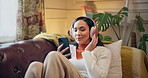 Happy girl, relax and phone with headphones on sofa for music, listening or audio streaming at home. Young, female person and break with mobile smartphone or sound app for radio or podcast at house