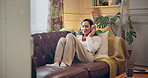 Happy girl, phone and lying with headphones on sofa for music, listening or audio streaming at home. Young, female person and relax with mobile smartphone or sound app for radio or podcast at house