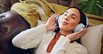 Happy girl, dancing and lying with headphones on sofa for music, listening or audio streaming at home. Young, female person and relax with headset for sound app, radio or podcast on couch at house