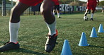 Legs, person and cone with soccer outdoor for fitness warm up, running practice and exercise performance. Athlete, beacon and speed challenge for football, agile formation and sport training on field