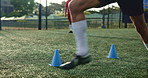 Feet, person and cone with soccer outdoor for fitness warm up, running guide and exercise performance. Athlete, sports beacon and speed challenge with football, coaching and game training on field