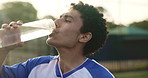 Sports, soccer and man in stadium for drinking water, hydration and wellness after training for game. Football field, male person and player on break with h2o liquid, practice and beverage for thirst