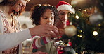 Happy family, child and decorate on Christmas tree for festive, holiday and celebration in home. People, bonding and daughter with ornaments, lights and living room as parents on vacation in December