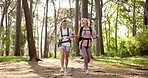 Mother, daughter and hiking with backpack in forest for fitness adventure, talking or bonding in nature. Mature woman, girl and laughing with trekking in woods for cardio exercise, explore or walking