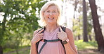 Mature, happy woman and hiker with backpack in nature for hiking, adventure or outdoor journey. Portrait, senior or female person with smile in joy for travel bag, walk or sightseeing in forest