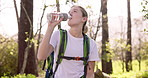 Happy woman, hiker or drinking water with backpack in forest for break, hydration or rest in wilderness. Young, female person or relax with mineral liquid for natural sustainability on hiking journey