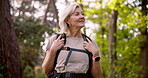 Mature woman, happy and hiking in nature for fitness, exercise and adventure with trees, explore and hobby. Female person, backpack and smile in forest for retirement, workout and travel with journey