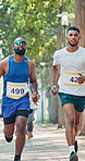 Running, nature and men in marathon with group for outdoor exercise, competition or fitness. Sports, energy and male athlete friends with cardio workout in race with crowd for contest in park.