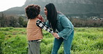 Mother, child and touch nose outdoor for love, care and bonding together on holiday in winter. Mom, kid and holding hands in nature for connection, talk or help stubborn boy with interracial family