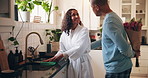 Couple, love and flowers in home for surprise, romantic gesture and kiss for anniversary milestone. Mature people, gift and bouquet in kitchen with care, healthy marriage and support in morning