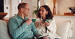 Couple, coffee break and talk in home living room on sofa, bonding and love together. Warm drink, headphones and happy man with woman and rest for weekend, relax and discussion on lounge couch