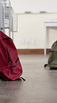 Backpack, floor and desks in empty classroom at school for lesson, education or learning. Scholarship, knowledge and bag for textbooks or study material for test, exam or assignment at academy.