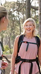 Nature, backpacking and woman with senior mother in forest for exploring, adventure or trekking. Laughing, walking and female person with elderly mom hiking outdoor in woods for exercise together.