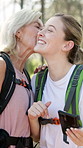 Woman, daughter and hiking in forest with kiss and phone map, internet navigation and travel direction. Mature mother, girl and smartphone in woods for path research, location or trekking break