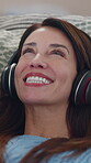 Mature, woman and dancing with headphones on couch for listening to music, radio app and audio playlist in home. Person, relax and happy on sofa in lounge for streaming subscription and favorite song