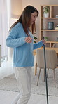 Happy woman, dancing and cleaning in home with broom, energy and playful on weekend for housekeeping. Female person, joyful and entertainment for relax, break and having fun in living room for chores