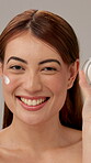 Woman, face and cream for beauty in studio with laughing, skin wellness and hyaluronic acid for hydration. Model, girl and portrait with creme for skincare and product promotion on gray background