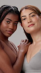 Confident, women and face with skincare in studio for natural beauty, cosmetics and facial glow. Friends, relax and pride with satisfaction by gray background for dermatology, treatment and shine