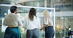 Business women, back and meeting with glass board for financial planning, expenses or analysis at office. Female people, team or employees with strategy for corporate revenue or budget at workplace