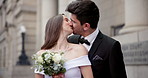 City, building and happy couple at wedding with kiss, flowers and bride with groom in street together. Urban romance, man and woman with court marriage, commitment and outdoor celebration of love.