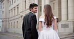 Couple, walking and kiss for wedding, marriage and love together with back, joy and commitment in city. Bride, groom and holding hands outdoor for relationship, romance and celebration with ceremony
