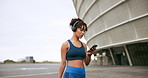 Woman, walking and fitness with smartphone, headphones and typing with social media. Outdoor, person and athlete with headset, mobile user and cellphone with communication, listening to music and app