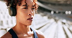 Woman, runner and warm up with headphones at stadium for race, sprint or workout preparation. Young, female person or serious athlete with headset for stretching, music or getting ready for fitness