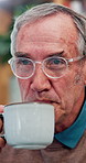 Thinking, coffee and senior man in home for calm morning drink, comfort and peace in retirement. Relax, nostalgia and elderly person in apartment with tea cup, memory and hot beverage in living room