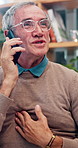 Senior man, chest pain and phone call in home for healthcare, consultation and explain symptoms. Pensioner, discomfort and mobile in living room for doctor appointment, feedback or medical assistance