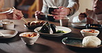 Food, sushi and hands of people at table with Asian cuisine, seafood and dumplings for eating together. Family, healthy and closeup of Japanese meal for nutrition at lunch, dinner and supper in home