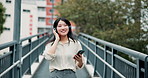 Japanese woman, headphones and mobile phone in city for music, walking or entertainment on app. Female person, technology and happiness with radio, audio or streaming for listening or online playlist