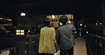 Back, walking or couple in city for travel or romance for anniversary, holding hands or love. Bridge, night and people bonding in relationship on adventure, date or valentines day in Tokyo, Japan