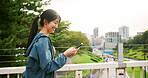 Fitness, happy woman and phone in city for social media, exercise blog or status update in Tokyo. Japanese influencer, smile or mobile on bridge for follower interaction, walking or check workout app