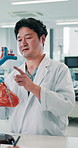 Students, man and doctor pointing at heart model for teaching, learning and advice at healthcare university. Cardiology, anatomy and Japanese medical professor in class for education, notes and study